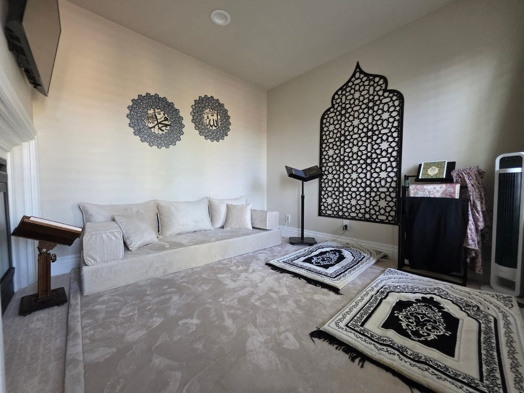 A customer's prayer room: a large black openwork mihrab panel on the wall, Allah and Muhammad medallions, prayer rugs on the floor and a Qur'an stand