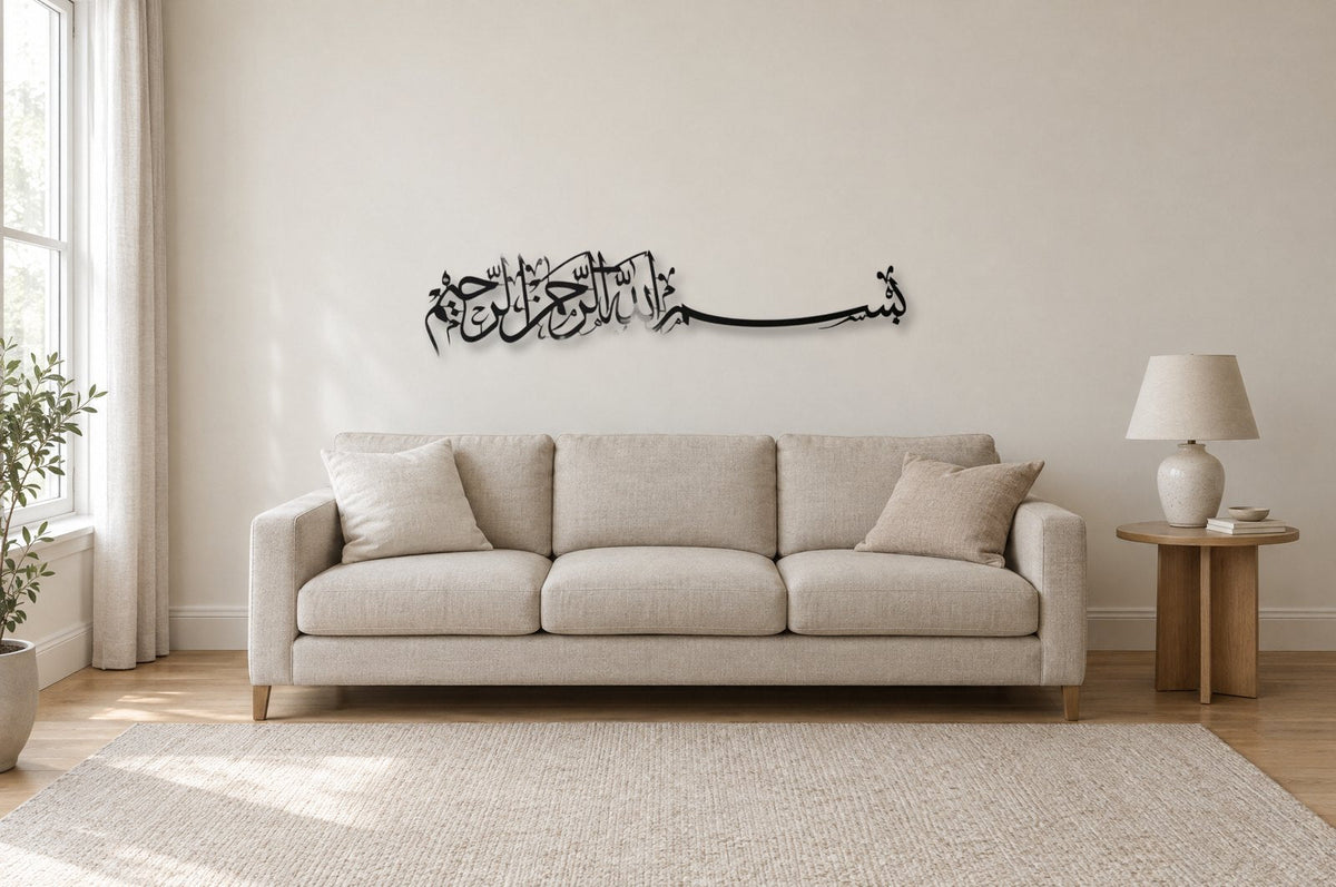 A black metal horizontal Bismillah calligraphy panel, 130 cm wide, hung about 20 cm above a three-seat linen sofa in a light living room