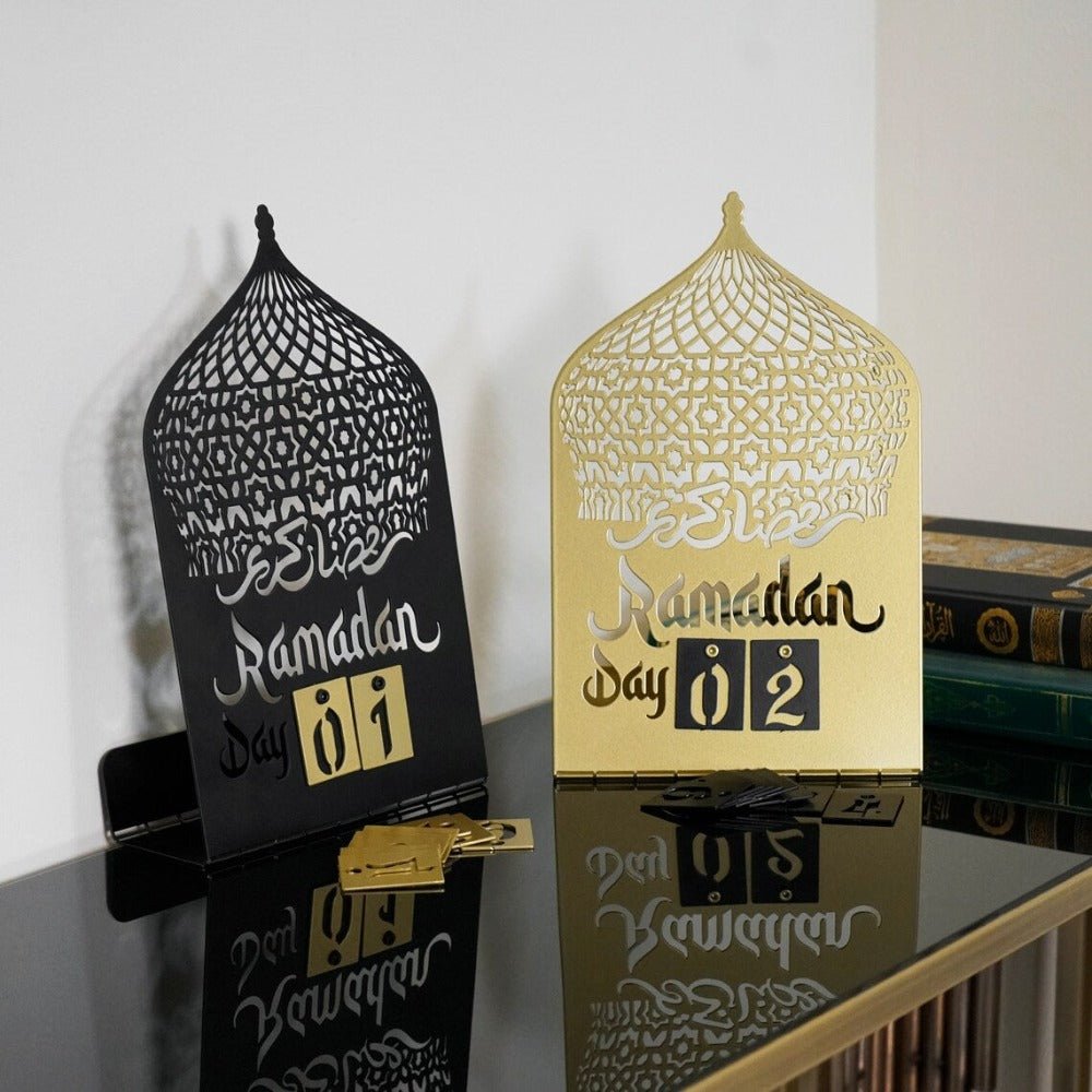 Two arched Ramadan countdown calendars on a glossy console, one black and one gold, showing Ramadan Day 01 and Day 02 in number tiles