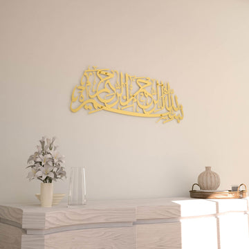 Matte Metall-Wandkunst mit Bismillah in Gold, an einer cremefarbenen Wand, Vorderansicht mit Lilienvase