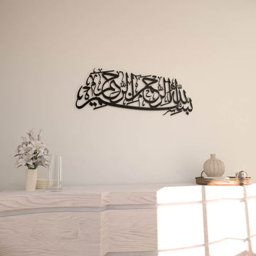 Matte Metall-Wandkunst mit Bismillah in Schwarz, an einer cremefarbenen Wand, Vorderansicht mit runder Vase rechts