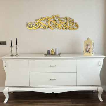 Gold Surah Ar-Rahman 13th verse calligraphy wall art, wide view over a console with curved legs