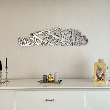 Silver acrylic Surah Ar-Rahman 13th verse calligraphy wall art above a white console