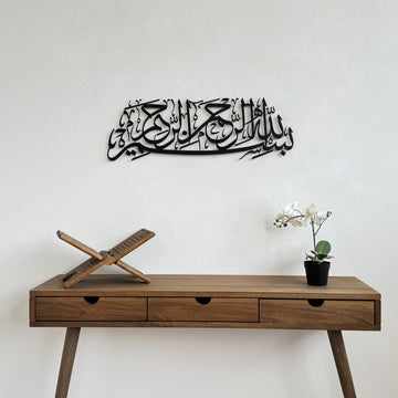 Matte Metall-Wandkunst mit Bismillah in Schwarz, über einem hölzernen Konsolentisch mit Koranständer