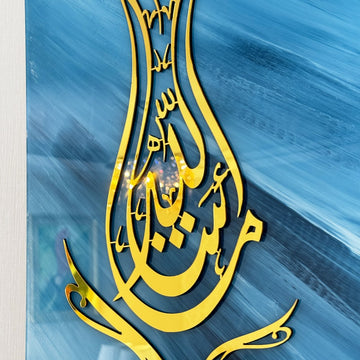 Gros plan de la calligraphie Mashallah dorée en forme de tulipe sur un fond de verre bleu à coups de pinceau
