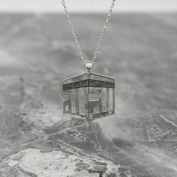 Collier pendentif Kaaba argenté suspendu au-dessus d'une surface en marbre gris