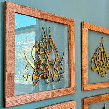 لقطة مقربة للوحة زجاجية لا إله إلا الله بإطار من خشب البلوط، خط ذهبي بجوار لوحة سبحان الله