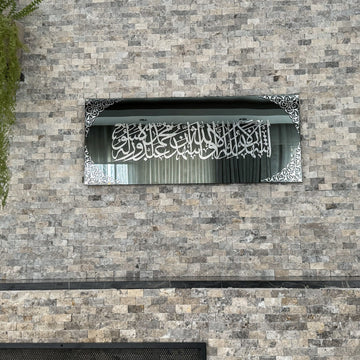 Kalima-Shahada-Glaskunst in silbernem Acryl auf schwarzem Spiegelglas, Vorderansicht aus mittlerer Entfernung an einer Steinwand