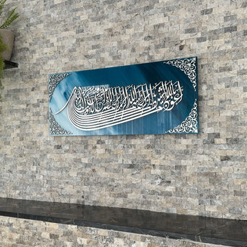 لوحة زجاجية أزرق وأبيض بالاستعاذة والبسملة بخط أكريليك فضي، منظر من اليسار على جدار حجري