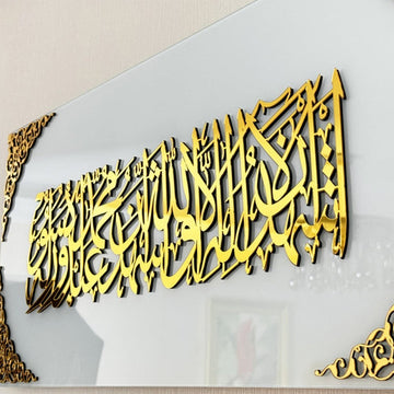 Nahaufnahme der Kalima-Shahada-Kalligraphie in goldenem Acryl auf einfarbig weißem Glas mit goldenem Eckornament