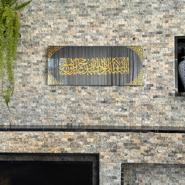 Kalima-Shahada-Glaskunst in goldenem Acryl auf schwarzem Spiegelglas, Vorderansicht an einer Steinwand