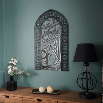 Mihrab Surah Rahman verse 13 metal wall art with shiny silver calligraphy on a teal wall above a sideboard