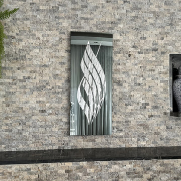 Vertical Allah calligraphy tempered glass wall art with Silver Acrylic script on black glass, on a stone wall