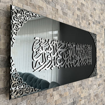 Nahe Schrägansicht der Kalima-Shahada-Kalligraphie in silbernem Acryl auf schwarzem Spiegelglas, das den Raum spiegelt