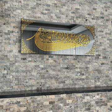 خط الاستعاذة والبسملة الأكريليكي الذهبي على شكل سفينة على زجاج داكن، جدار حجري مع انعكاس الغرفة