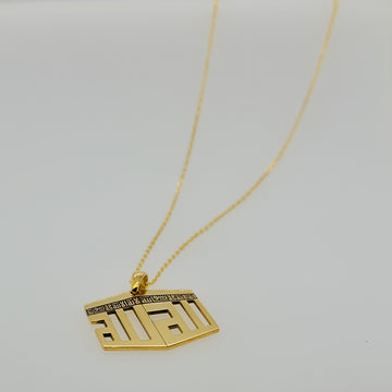 Collier pendentif Kaaba doré posé à plat sur une surface claire, la chaîne déroulée