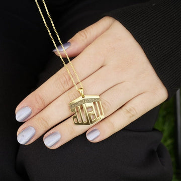 Collier pendentif Kaaba doré posé sur une main, avec une chaîne fine