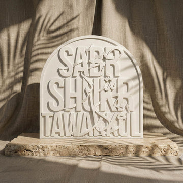 Relief de pierre Sabr Shukr Tawakkul en lettres latines et arabes sur une plaque blanche cintrée, vue de face