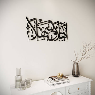 Ahlan wa Sahlan Metall-Wandkunst in Schwarz an weißer Wand über einem weißen Sideboard