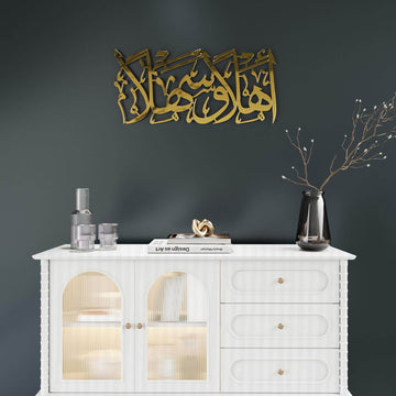 Goldene Ahlan wa Sahlan Metall-Wandkunst über einem weißen Sideboard, weite Ansicht der ganzen Wand