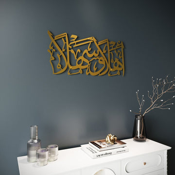 Goldene Ahlan wa Sahlan Metall-Wandkunst an dunkelgrauer Wand, schräge Ansicht über einem Sideboard