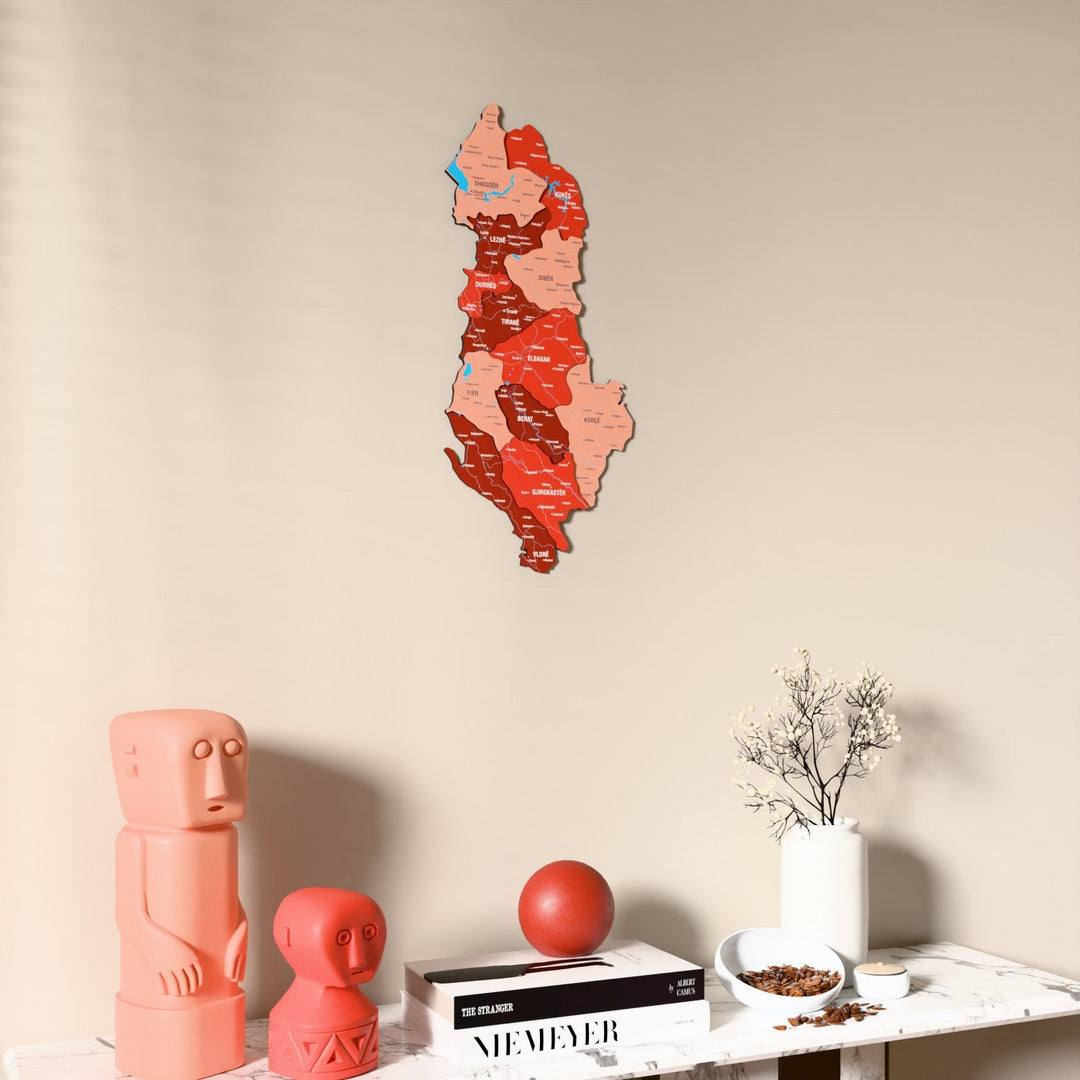 Flag colored Albania wooden wall map on a beige wall above a console with figurines