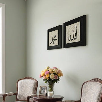 Black Allah and Muhammad stonecast calligraphy wall art set hung from the side angle above two armchairs