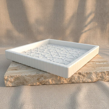 Quadratisches maurisches Steinrelief-Tablett mit gerippter Außenkante, Schrägansicht auf einem Travertinblock