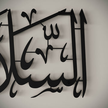Gros plan de la calligraphie en métal noir As-Salamu Alaykum, montrant les vis de fixation murale