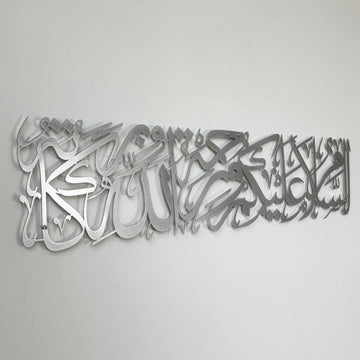 Silver metal Assalamu Alaikum calligraphy, close side angle on a gray wall