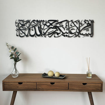 Black Assalamu Alaikum Wa Rahmatullahi Wa Barakatuh metal wall art above a wooden console with a vase