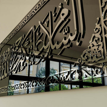 Close-up of silver raised calligraphy on the black glass Assalamu Alaikum wall art, mirror reflections