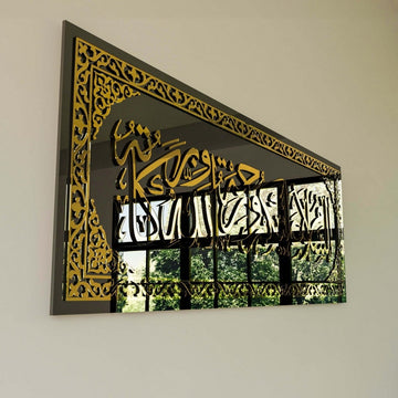 Close-up of gold border and calligraphy on the black glass Assalamu Alaikum wall art with a window reflection