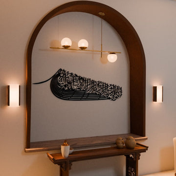 Black ship-shaped Auzu Basmala metal wall art in the arched niche, closer front view with wall lights