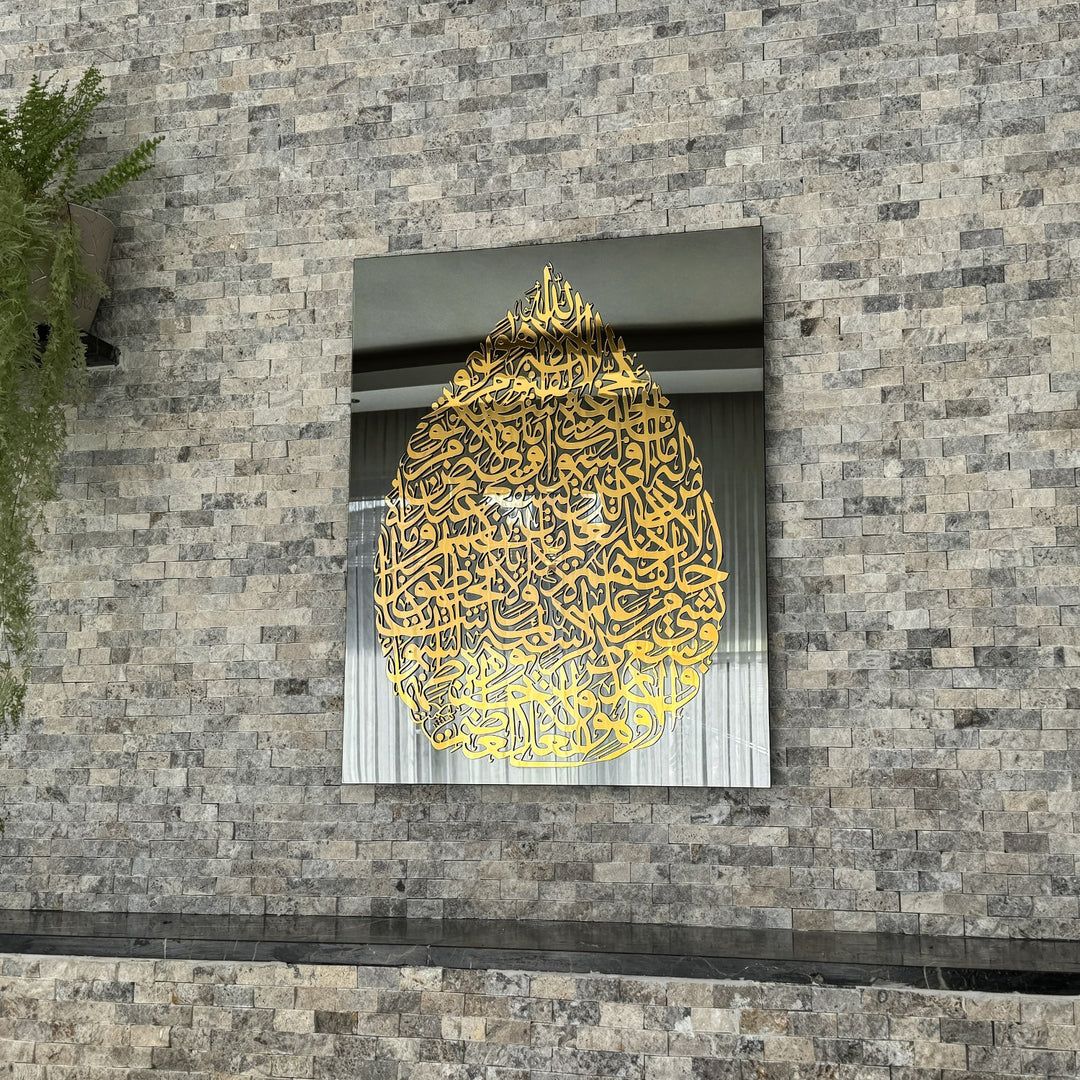 Art mural en verre Ayatul Kursi en forme de goutte, doré, sur miroir noir, vue moyenne sur un mur en pierre