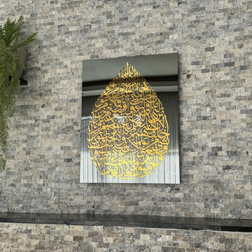 Art mural en verre Ayatul Kursi en forme de goutte, doré, sur miroir noir, vue moyenne sur un mur en pierre