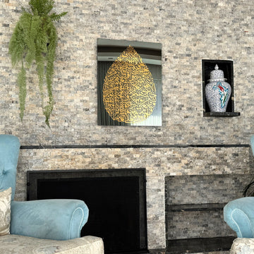 Art mural en verre Ayatul Kursi en forme de goutte, doré, vue large au-dessus d'une cheminée avec une plante suspendue