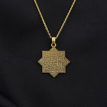 Gold octagonal Ayatul Kursi necklace pendant on a chain against black fabric