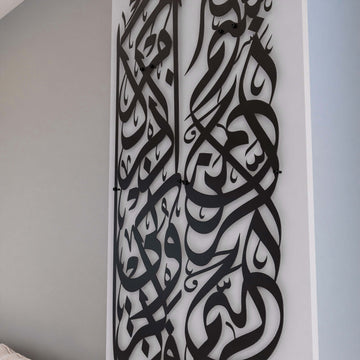 Gros plan des colonnes de calligraphie en métal noir avec Basmala et sourate Baqarah 152 sur un mur