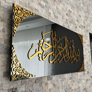 Schräge Nahaufnahme der goldenen Acryl-Kalligraphie Bismillah und der Eckornamente auf schwarzem Spiegelglas