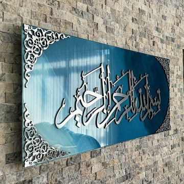 Schräge Nahaufnahme der silbernen Acryl-Kalligraphie Bismillah und der verzierten Ecken auf blau-weißem Glas