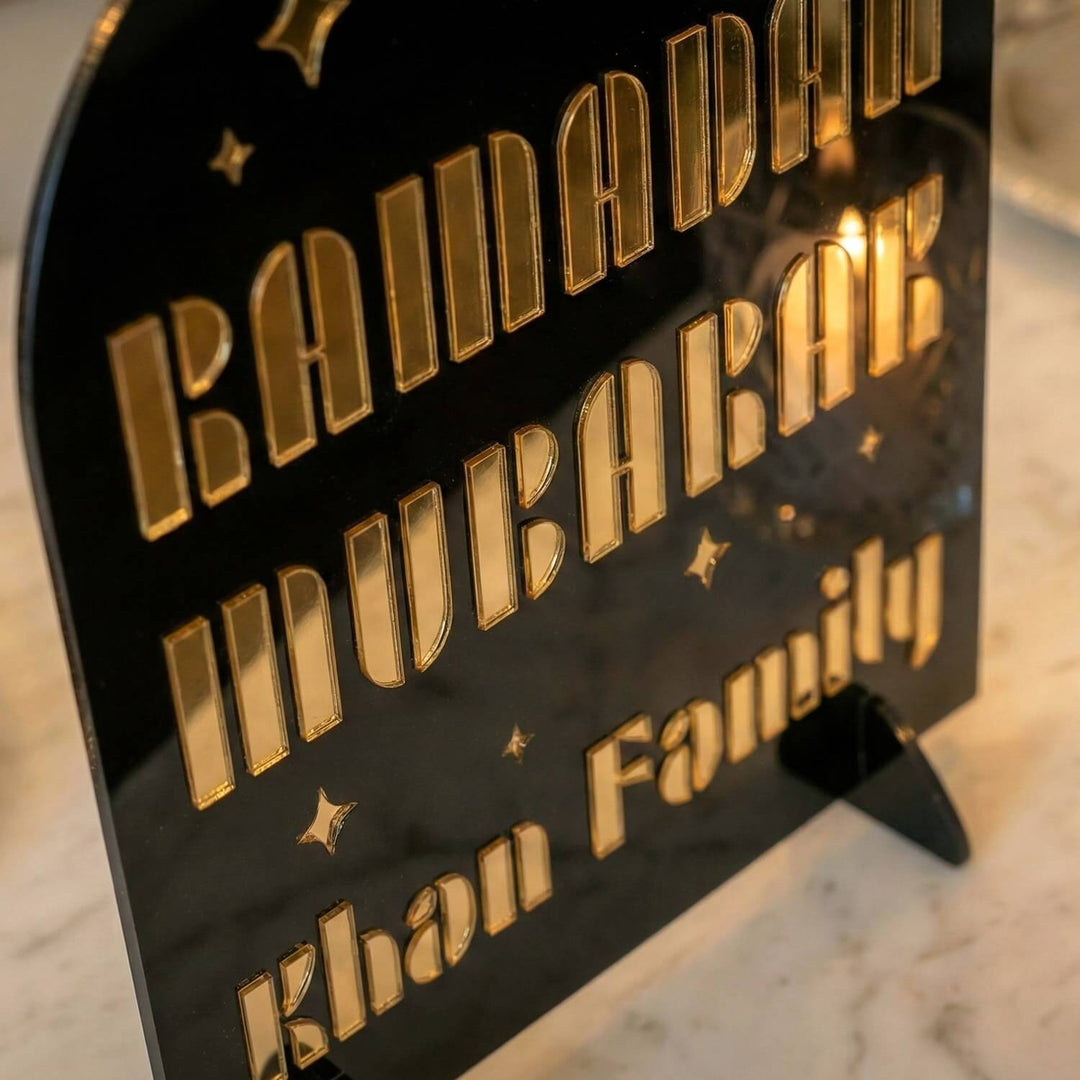 Nahaufnahme der goldenen Modern-Schrift und Familie Khan auf dem schwarzen Acrylaufsteller