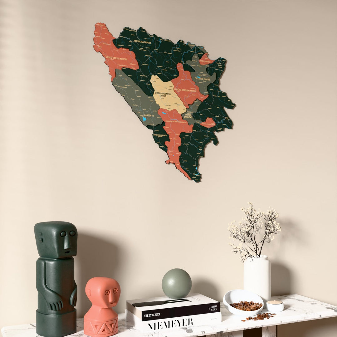 Sage Bosnia and Herzegovina wooden wall map on a beige wall above a console with figurines