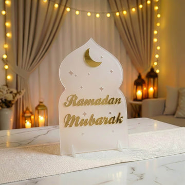 Ramadan-Mubarak-Acrylaufsteller in Schrift-Design, Gold auf Frostweiß, Vorderansicht mit Laternen dahinter