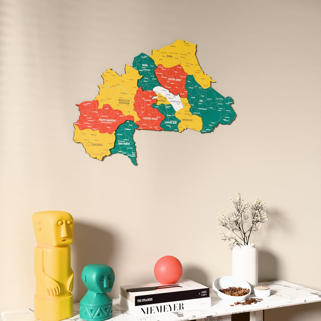 Flag colored Burkina Faso wooden wall map on a beige wall above a console with figurines