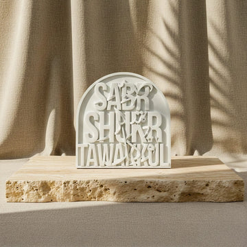 Vue de face réduite de la plaque Sabr Shukr Tawakkul en relief de pierre sur une dalle, fond de lin