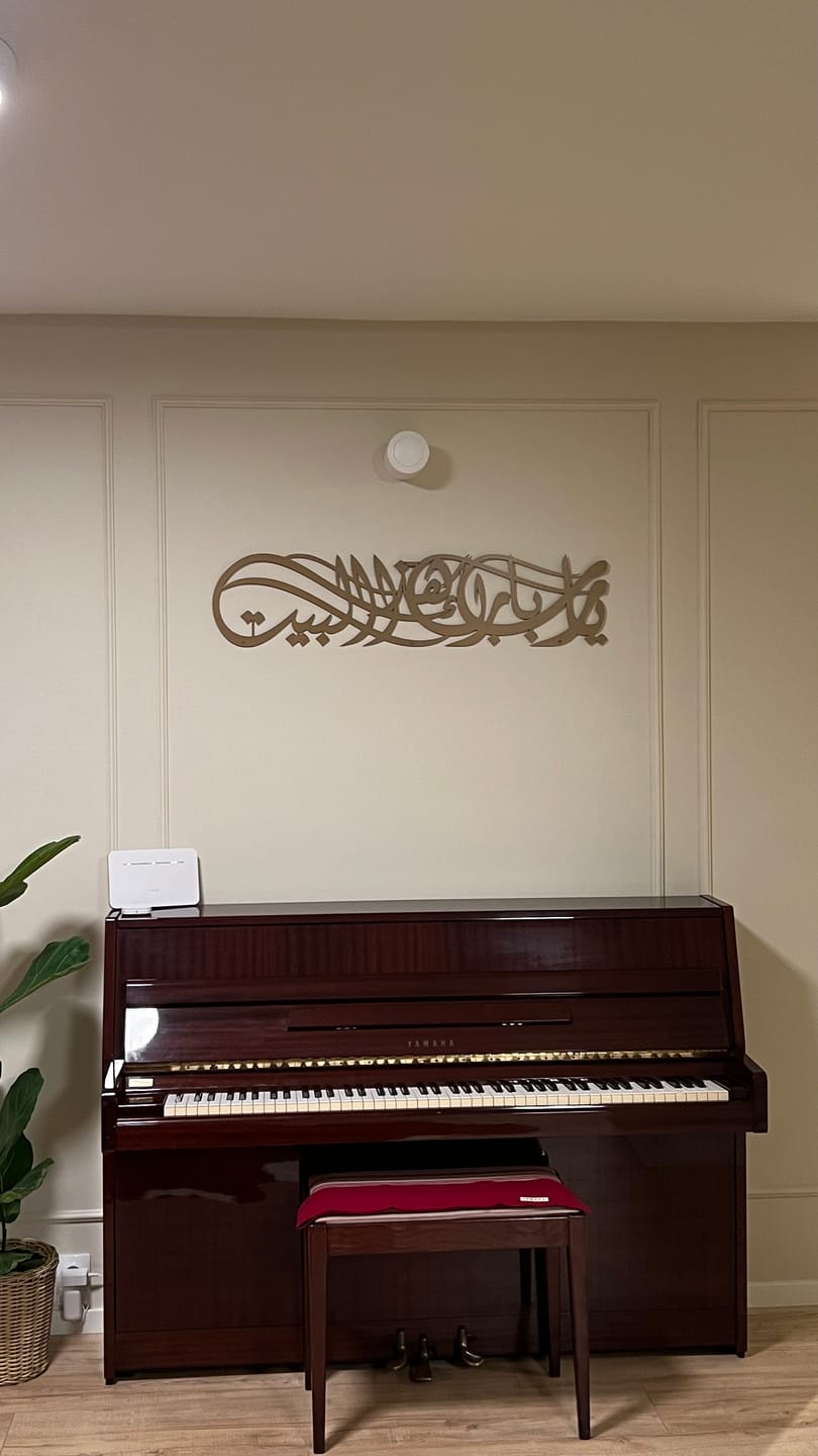 Customer photo of gold Arabic calligraphy wall art above a piano