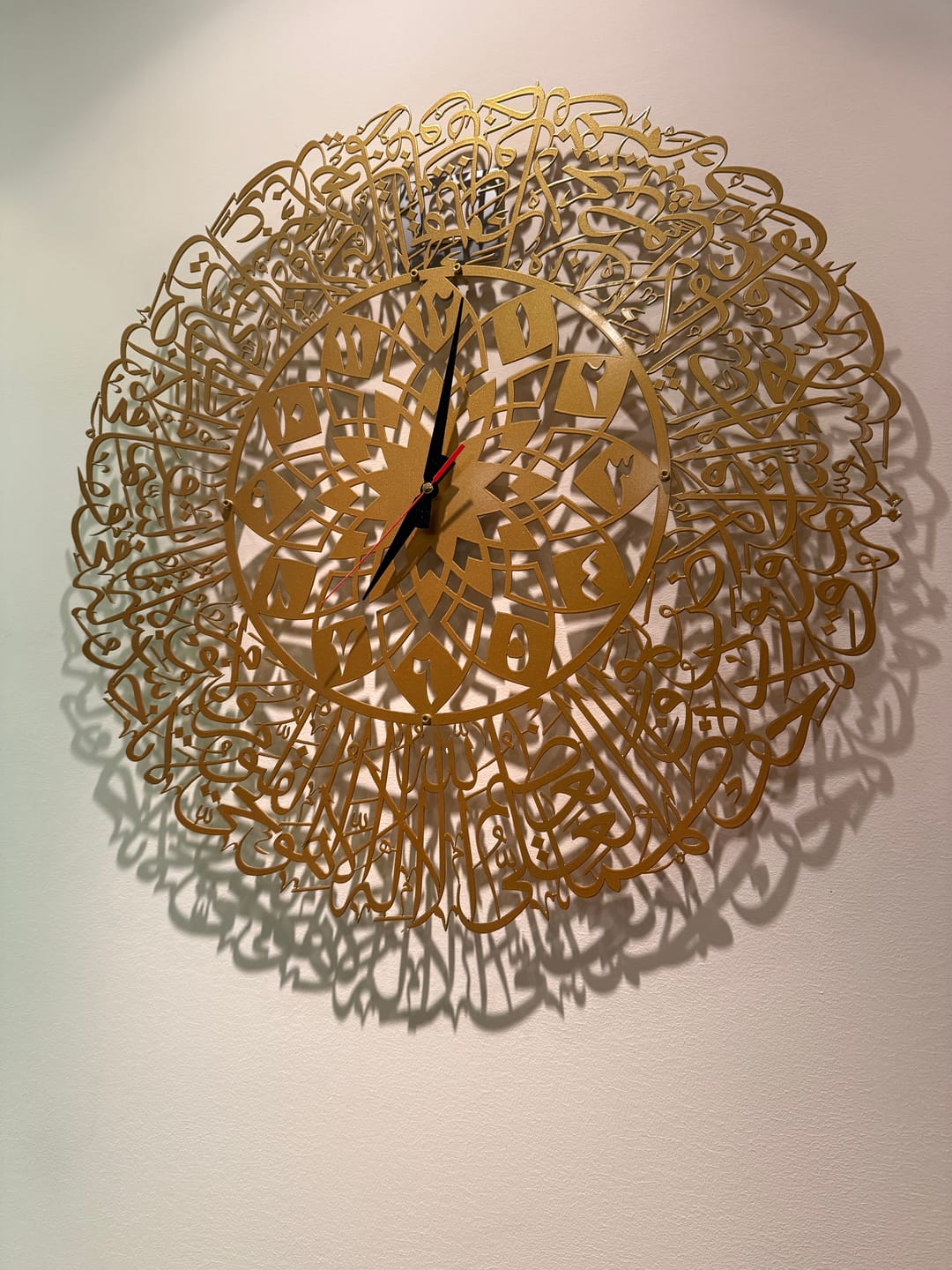 Customer photo of a round gold Arabic calligraphy wall clock casting shadows
