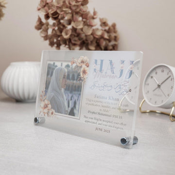 Design 2 Hajj Mabroor table decor with floral frame and photo, angled view beside a clock