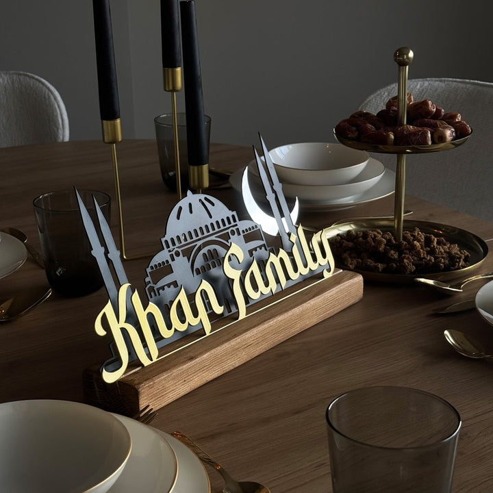 Decorative nameplate with 'Khan Family' on a dining table with plates and glasses.